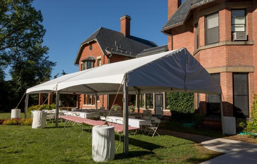 A.D. White House patio set up with tent and several tables for a summertime seated dinner.