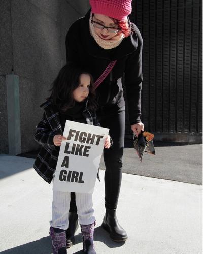 Image of young girl with her mother holding a sign that says &quot;Fight Like a Girl&quot;